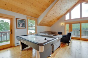 Una habitación amplia con mesa de billar, sofá y un gran ventanal con vistas al exterior.
