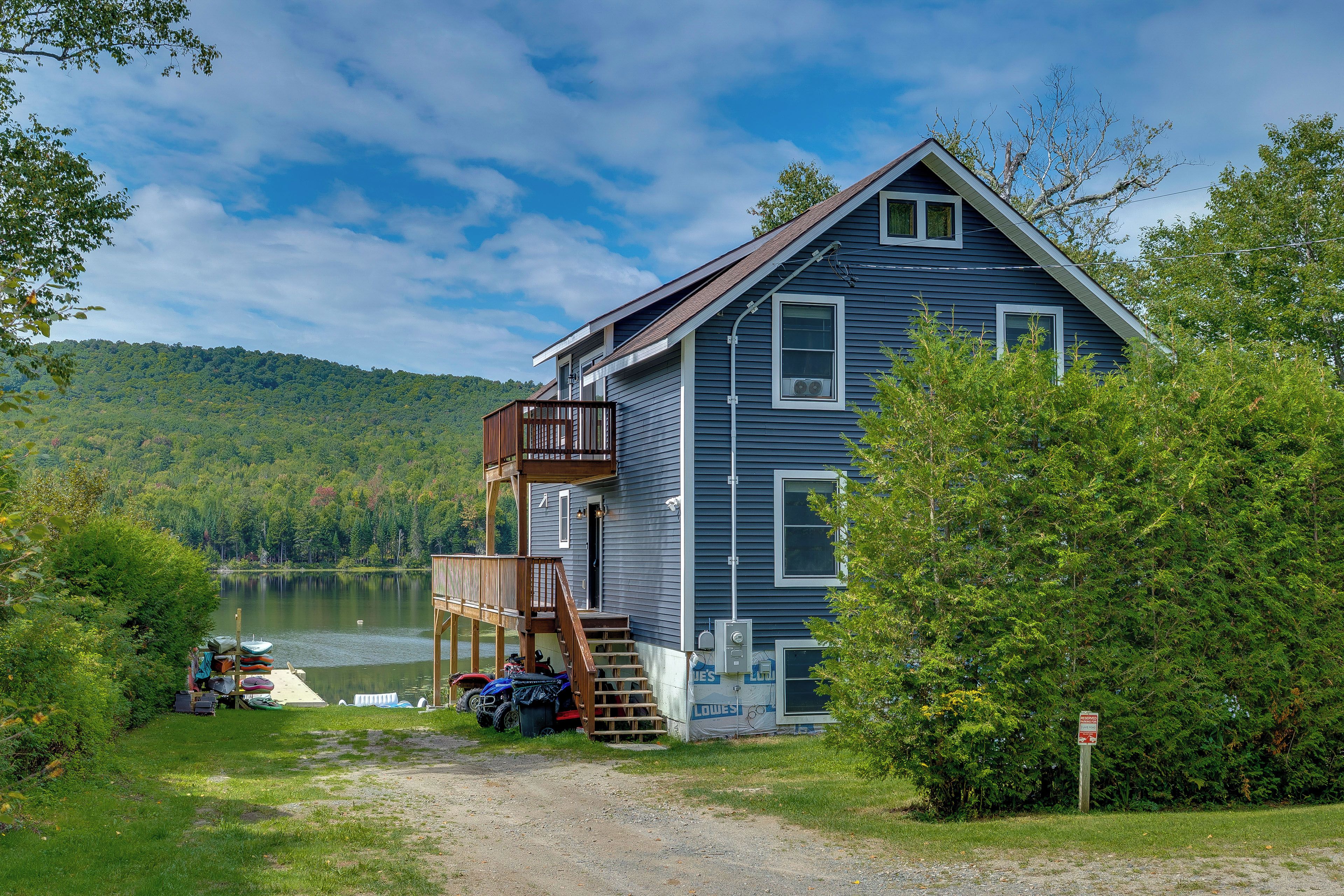A two-story house with a deck, a dock, and a lake view.