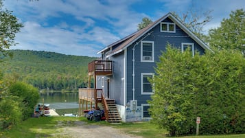 A two-story house with a deck, a dock, and a lake view.
