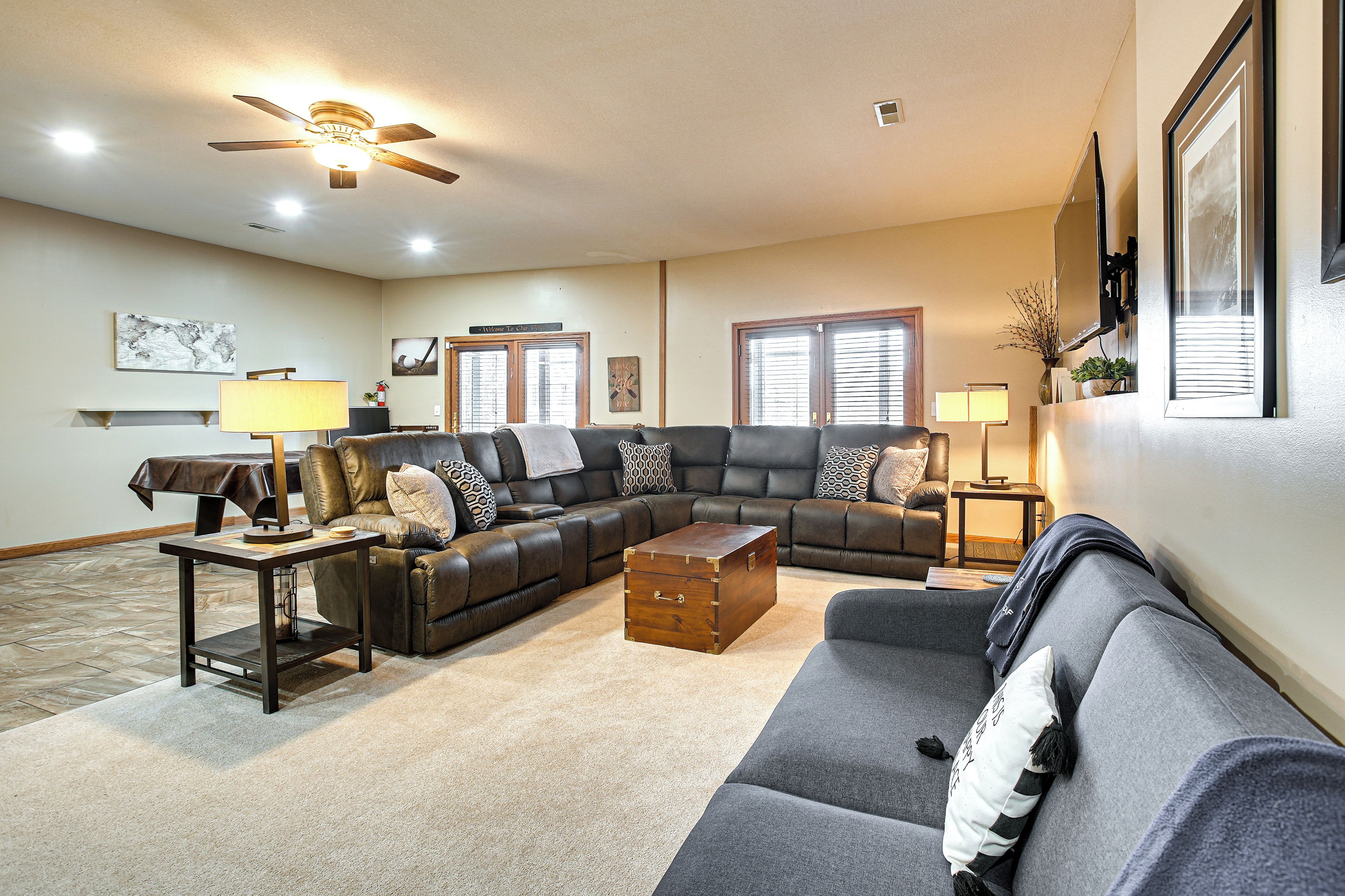 A living room with a sectional sofa, a coffee table, a ceiling fan, and a fireplace.