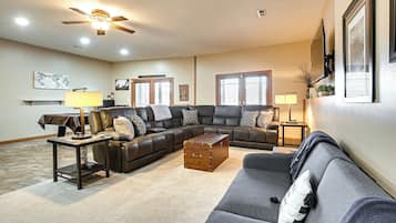 A living room with a sectional sofa, a coffee table, a ceiling fan, and a fireplace.