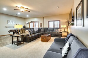 A living room with a sectional sofa, a coffee table, a ceiling fan, and a fireplace.