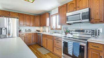 A modern kitchen with wooden cabinets, stainless steel appliances, and a large island.