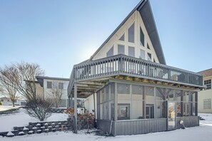 A modern building with a large glass facade, a balcony, and a snow-covered ground.