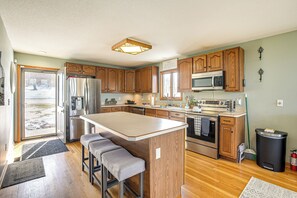 A modern kitchen with wooden cabinets, stainless steel appliances, and a large island with bar stools.