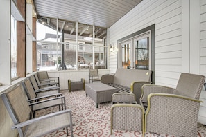 A covered patio area with wicker furniture and a patterned floor.