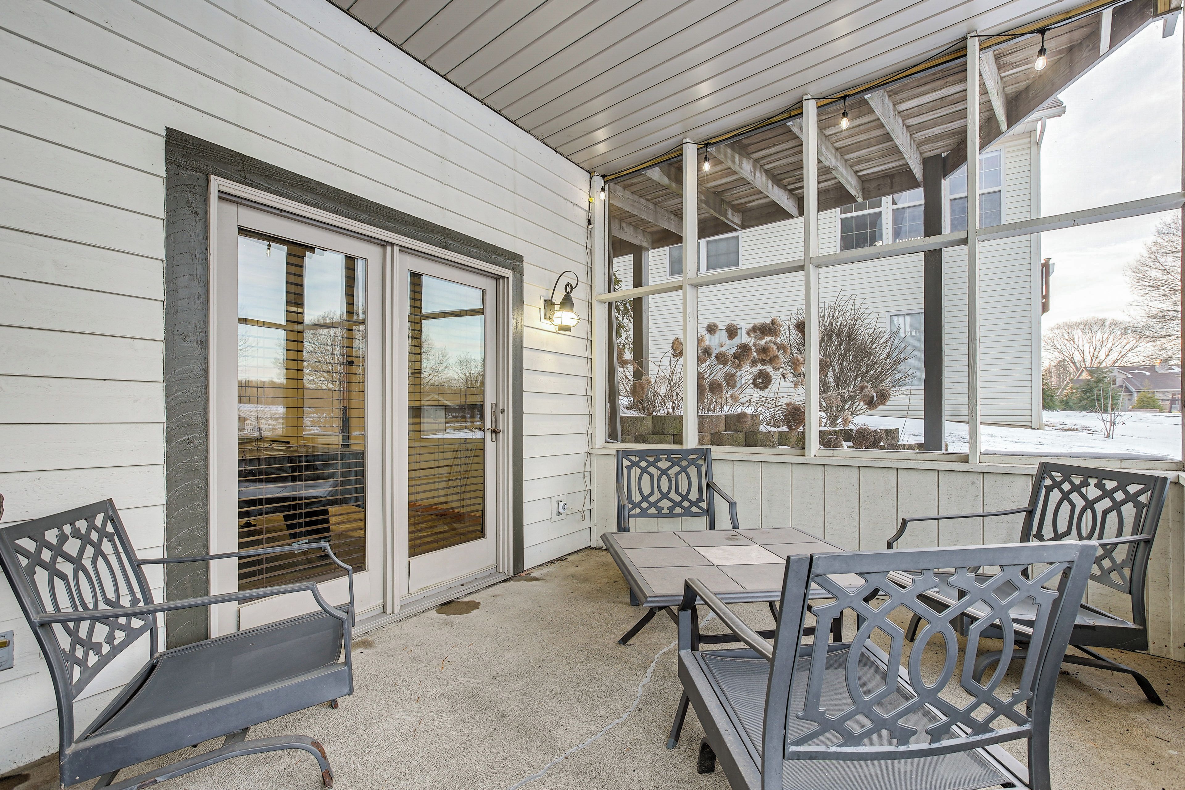 A covered patio with a table and chairs, a sliding glass door, and a view of the outside.