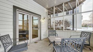 A covered patio with a table and chairs, a sliding glass door, and a view of the outside.