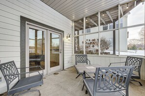 A covered patio with a table and chairs, a sliding glass door, and a view of the outside. - Game Room, Screened Porch! Howard A-frame Chalet (Howard)