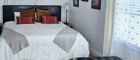 A neatly made bed with a headboard, a bedside lamp, and a small table.