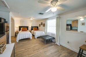 Een hotelkamer met twee bedden, een kitchenette, een plafondventilator en een zithoekje.
