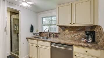 A kitchen with a built-in dishwasher, a double sink, and a coffee maker.