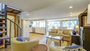 A spacious living area with a staircase, a kitchen in the background, and a sofa with a cushion.