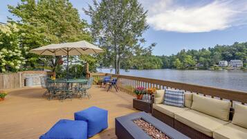 A deck with outdoor furniture, a fire feature, and a view of a lake.