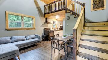 Un interior acogedor con un altillo con habitación, una zona de comedor y una cocina.