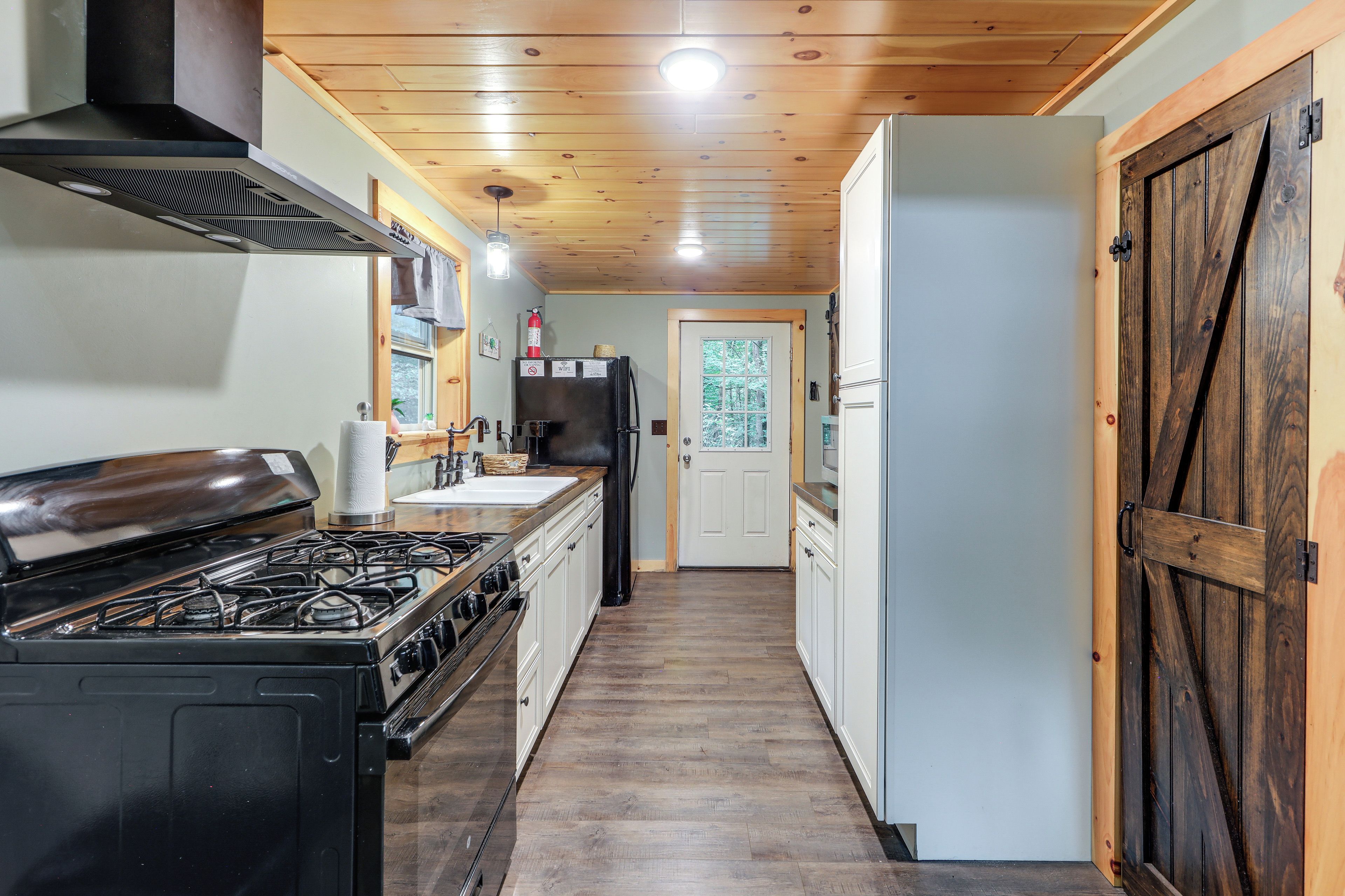 Una cocina con estufa a gas, refrigerador y muebles de madera.