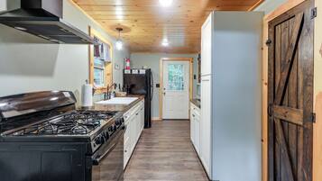 Una cocina con estufa a gas, refrigerador y muebles de madera.