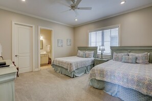 Quarto com duas camas, ventilador de teto, janela com persianas e porta de acesso a um banheiro.