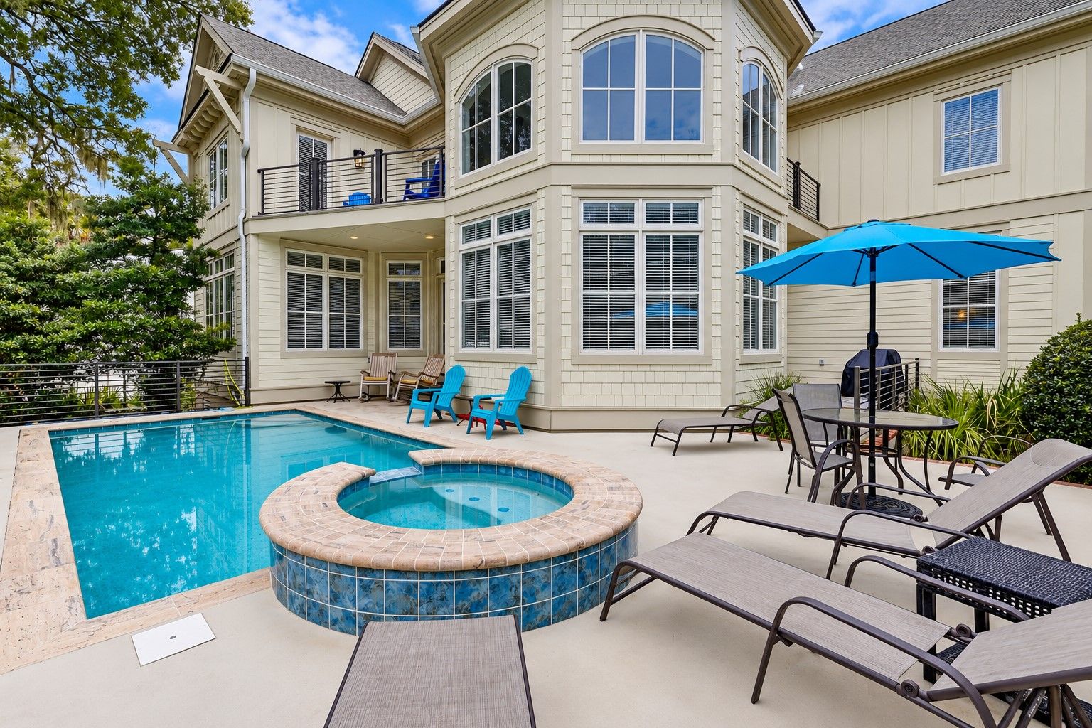Un patio trasero con piscina, jacuzzi y mobiliario de exterior.