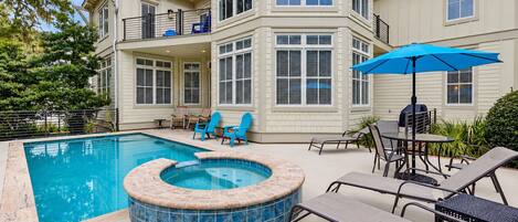 Un patio trasero con piscina, jacuzzi y mobiliario de exterior.