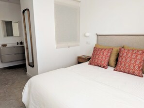 A bedroom with a bed, a nightstand, a mirror, and a window. - La Raiz Ocean Views, Volcanic Landscape & Terrace (Tías)