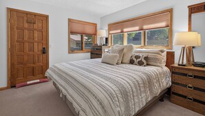 Ein Schlafzimmer mit einem großen Bett, einem Holz-Kopfteil, zwei Nachttischen mit Lampen, einer Holzkommode und einer Tür mit Schloss.