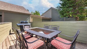 Eine Terrasse im Freien mit Tisch, Stühlen, einem Grill und einem Holzdeck.