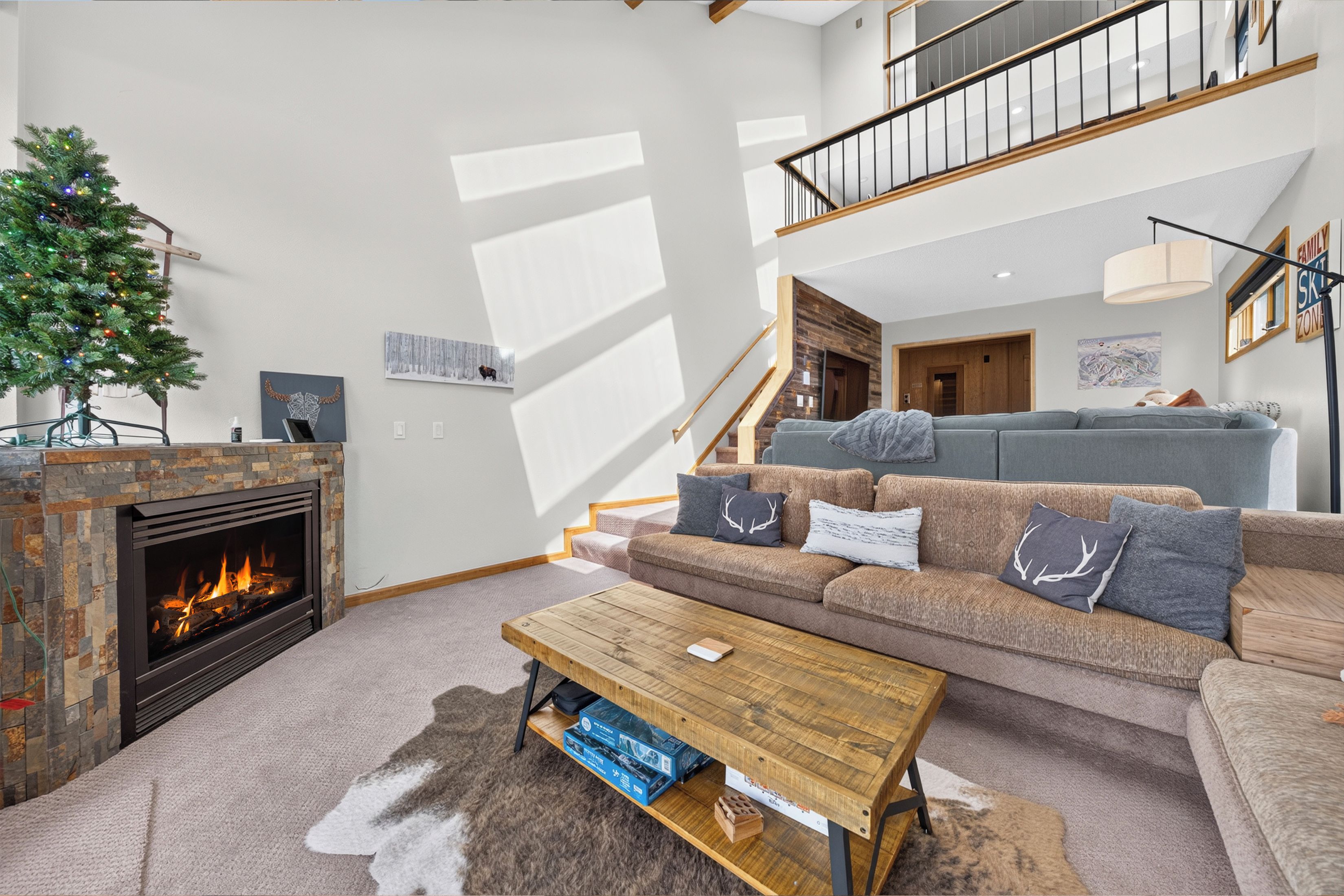 A living room with a fireplace, a sofa set, a coffee table, and a staircase leading to an upper level.