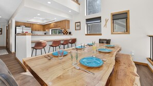 Eine moderne Küche mit Holzschränken und einem Essbereich mit einem großen Holztisch, gedeckt für sechs Personen.