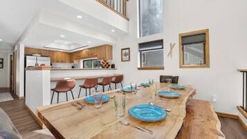 A modern kitchen with wooden cabinets and a dining area with a large wooden table set for six.