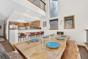 Eine moderne Küche mit Holzschränken und einem Essbereich mit einem großen Holztisch, gedeckt für sechs Personen.