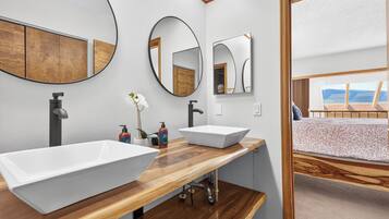 A modern bathroom with two vessel sinks, wooden countertops, and large mirrors.