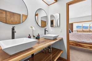 A modern bathroom with two vessel sinks, wooden countertops, and large mirrors.