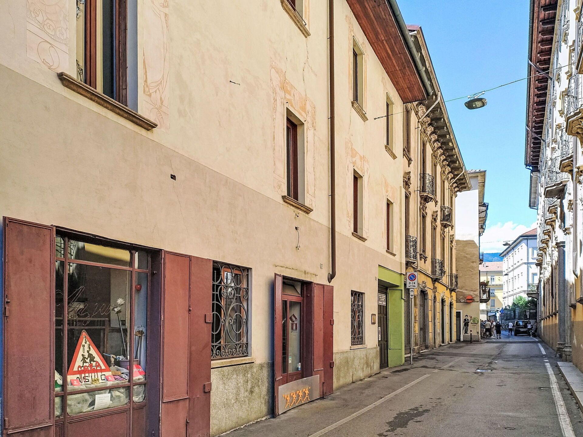 Une rue étroite bordée d’immeubles à l’architecture traditionnelle, avec des fenêtres et des portes bien visibles, et un ciel dégagé au-dessus.