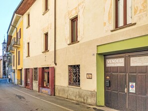 Straßenansicht eines Gebäudes mit einer grünen Tür, auf der 'VENDESI INTERO STABILE' steht, und einem Schild, das 'Erdgeschoss + 1. Stockwerk' anzeigt.