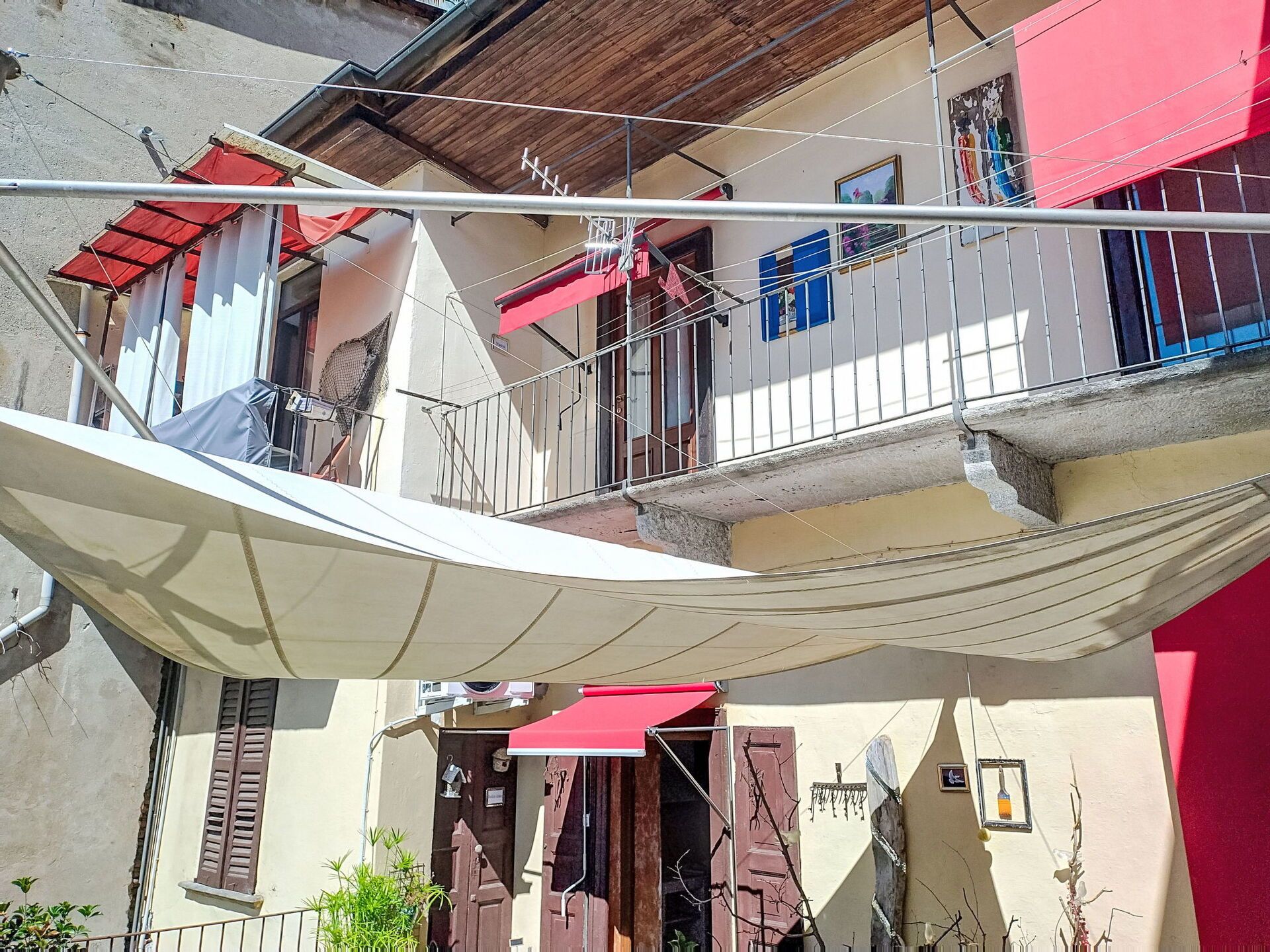 Un immeuble d’habitation doté d’un balcon, d’un auvent rouge et d’un auvent blanc.