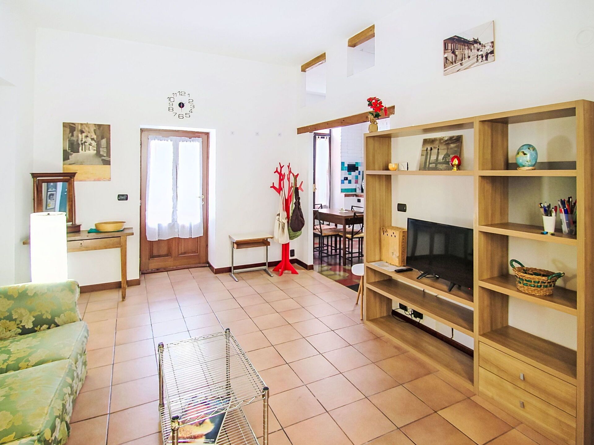 Una sala de estar con sofá, mueble para televisión y un comedor con sillas y mesa.