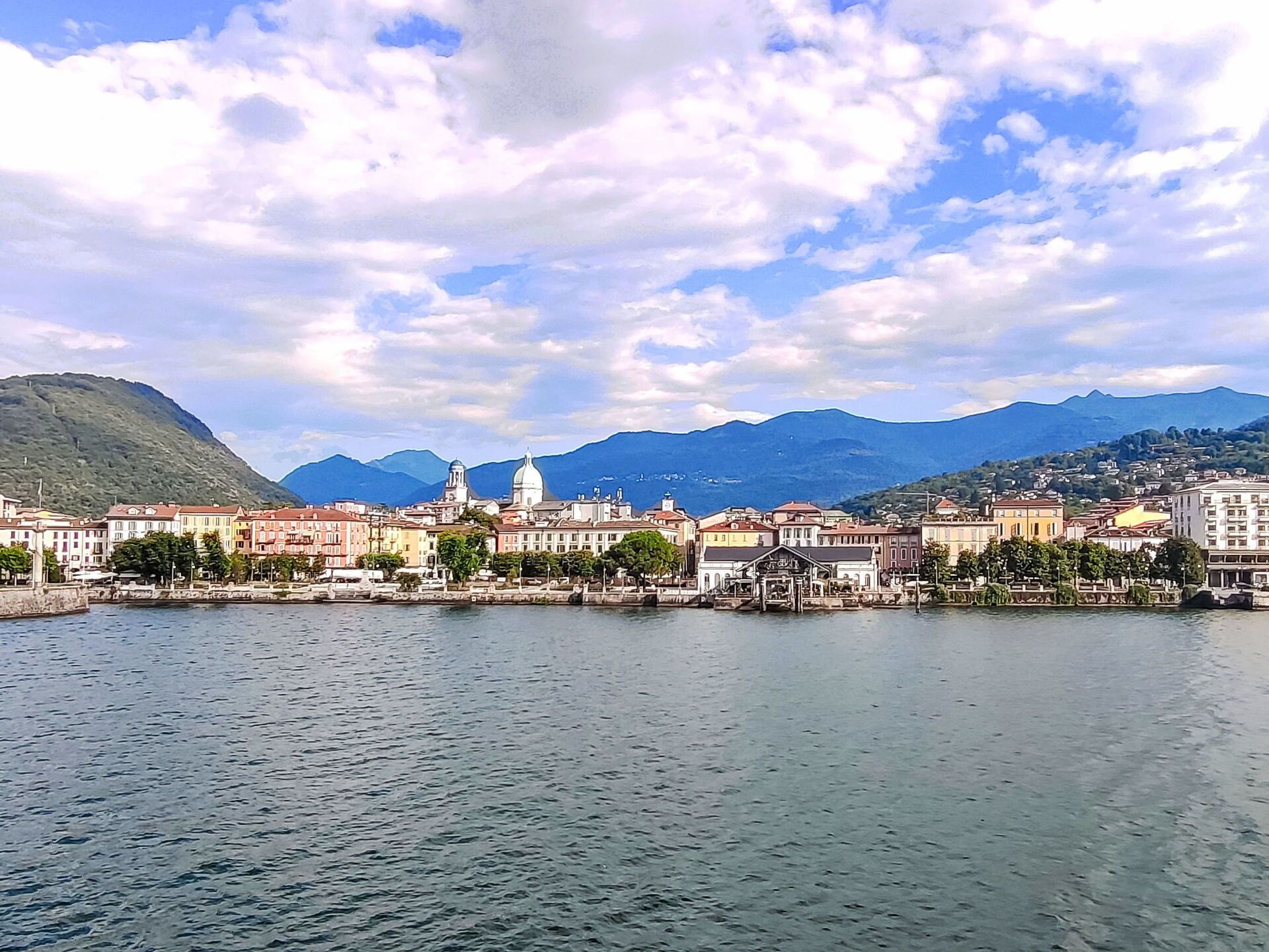 A waterfront cityscape with buildings, a prominent dome, and mountains in the background.