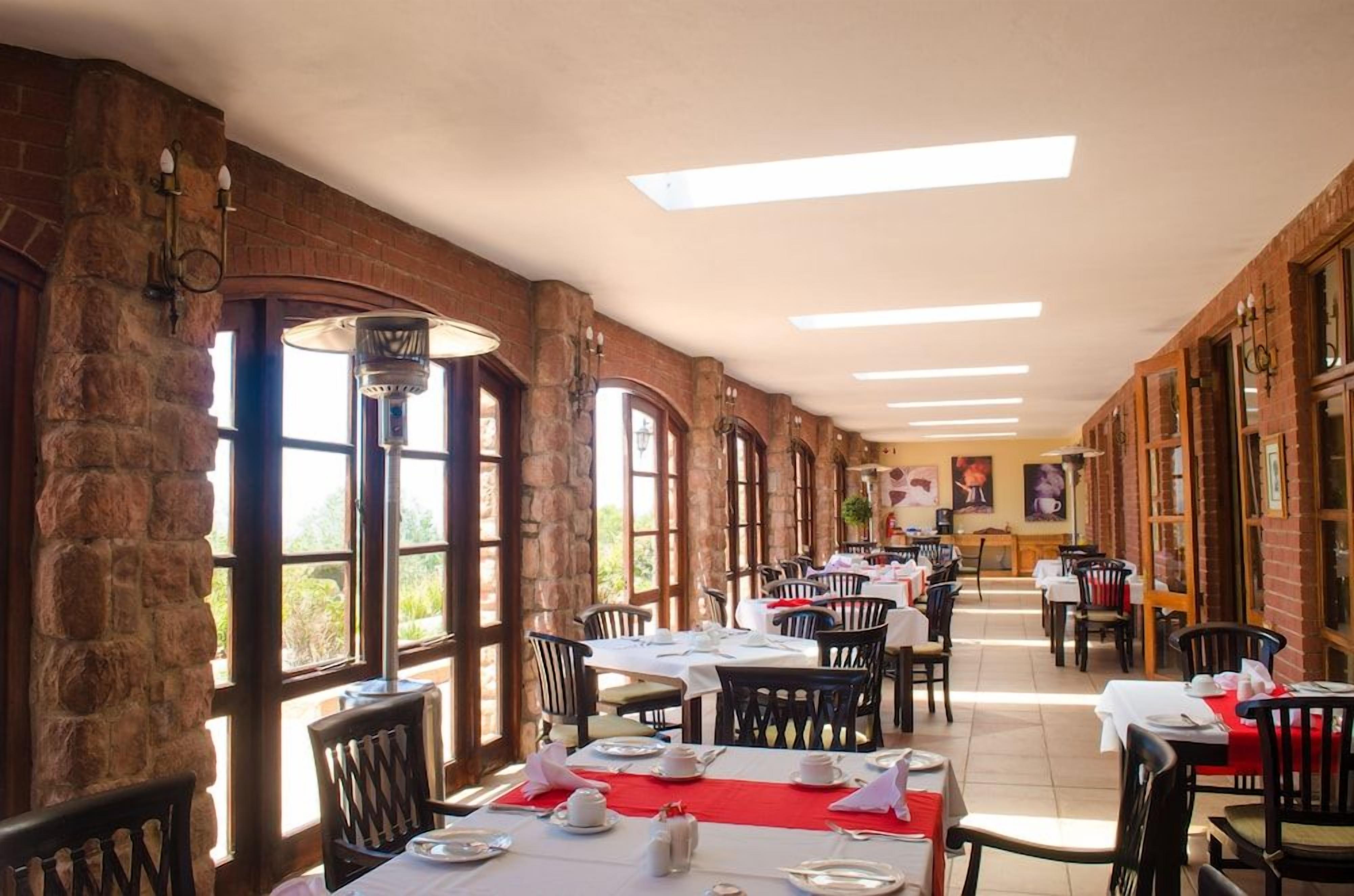 A restaurant with brick walls, large windows, and tables set for dining.