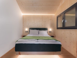 A modern bedroom with a wooden ceiling, a bed with a green blanket, two bedside tables, and a window with a view. - Beautiful private villa for 8 guests with TV and balcony (Brandstätter)
