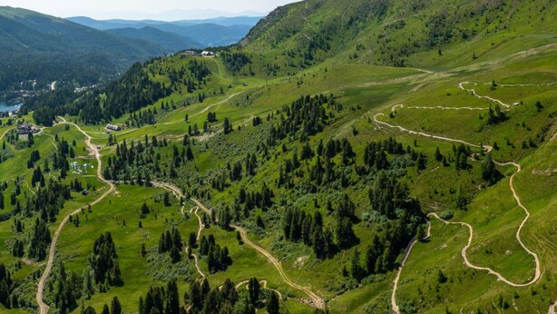 Paisagem montanhosa com trilhas sinuosas e edifícios dispersos.