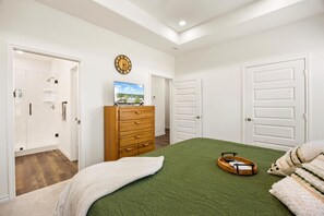 A bedroom with a bed, dresser, and a clock on the wall. - Lake House Game Garage - Fire Pit Sleeps 8 (Granbury)