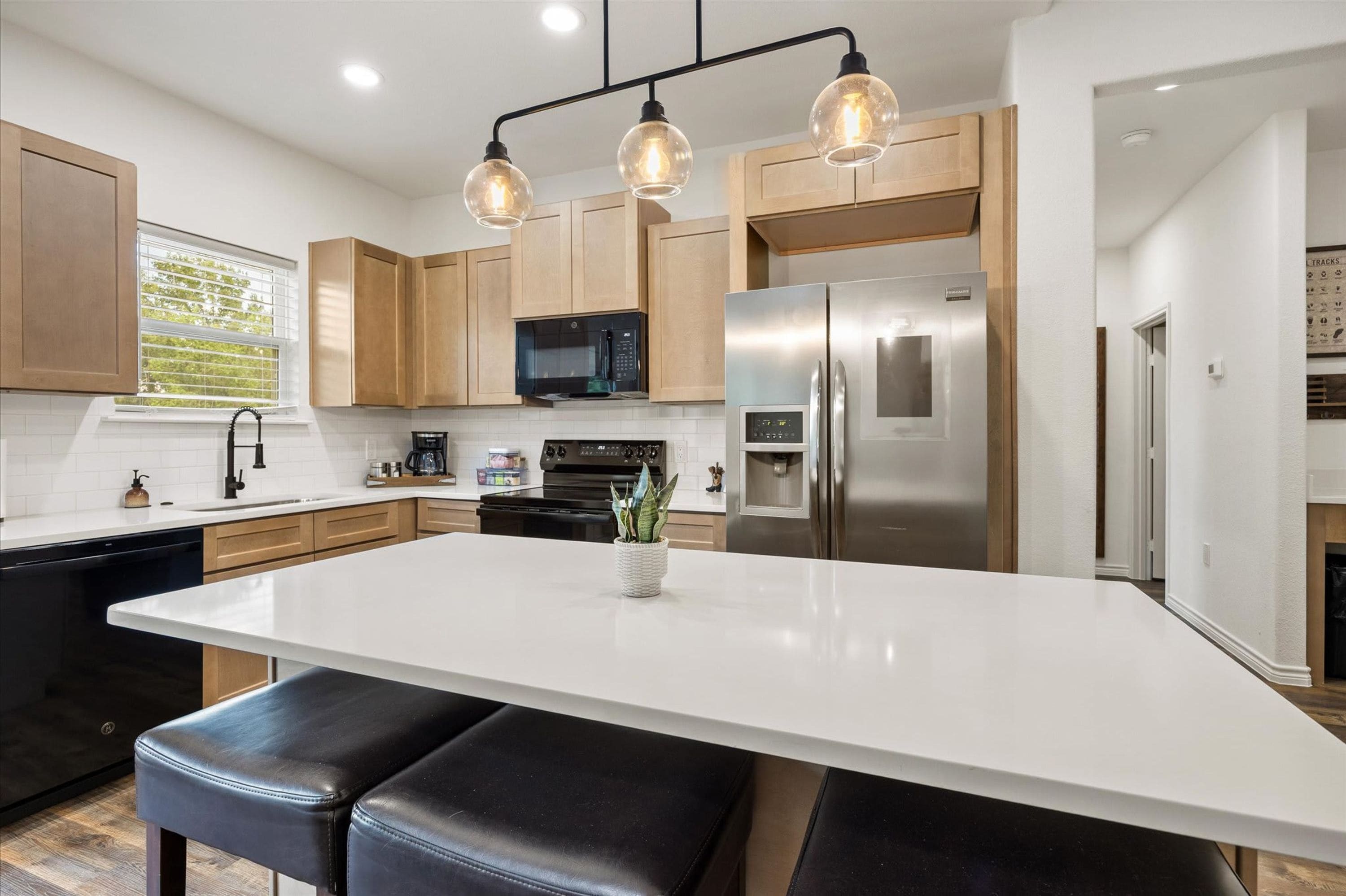 A modern kitchen with a central island, stainless steel appliances, and wooden cabinets.