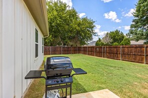 A backyard with a barbecue grill, a wooden fence, and a house. - Twin Lake Homes - Sleeps 16 Fire Pit Swing (Granbury)