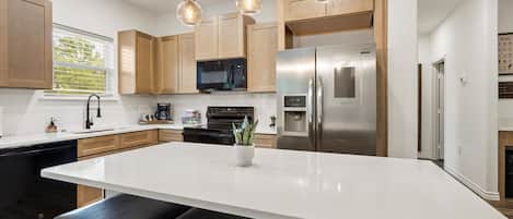 A modern kitchen with a central island, stainless steel appliances, and wooden cabinets.