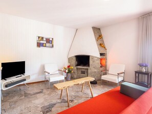Ein modernes Wohnzimmer mit Kamin, weißen Wänden und einem Flachbildfernseher.