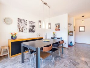 Ein moderner Essbereich mit einem langen Tisch, Stühlen und einer Küchenarbeitsplatte.