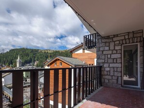 Ein Balkon mit einer Steinmauer und einem Holzgebäude im Hintergrund.
