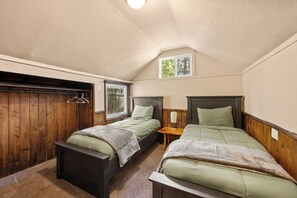 A room with two beds, wooden walls, a window, and a small table. - Walk to Lake & Village | Hot Tub, Fire Pit, Fenced Yard & Lake Views (Big Bear Lake)