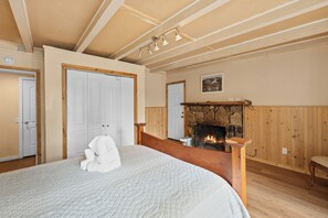Ein Schlafzimmer mit einem großen Bett, einem Kamin, Holzvertäfelung und einer Tür.